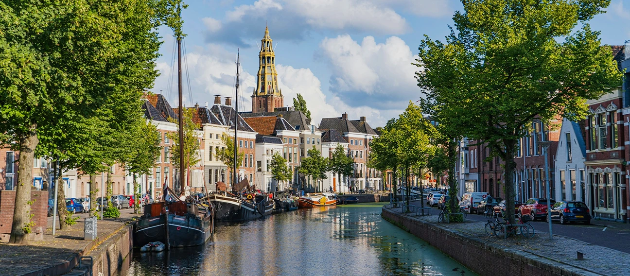Foto van een gracht in Groningen met huizen op de achtergrond.