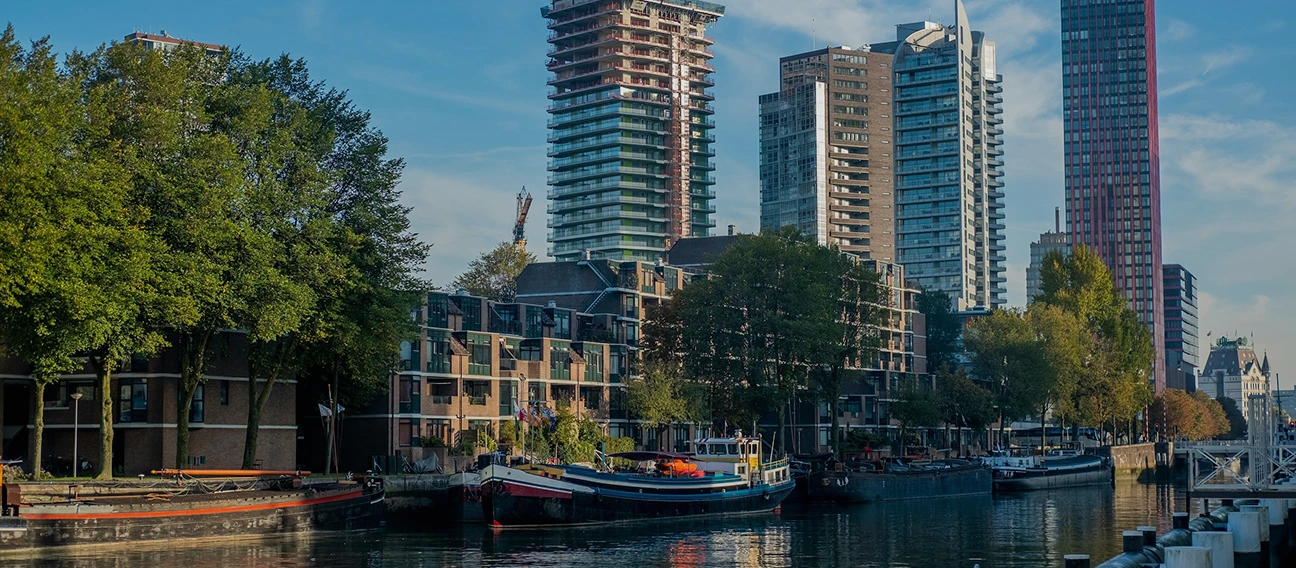 Foto van een gracht in Rotterdam met huizen en flatgebouwen op de achtergrond.